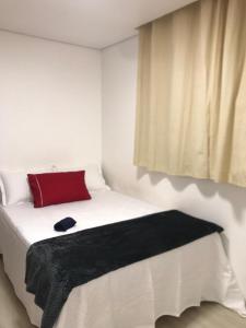 - un lit blanc avec un oreiller rouge et une fenêtre dans l'établissement AP ALPHA 5 STAr, à Vespasiano