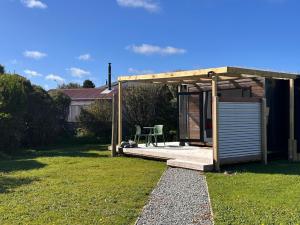 a shed with a table and a chair in a yard at The Wee Snug in Hokitika +14 photos