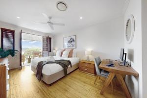 a bedroom with a bed and a desk with a computer at Penthouse at Colonial in Noosaville