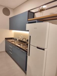 a kitchen with a white refrigerator and a sink at Apartamento novo em São Lourenço in São Lourenço