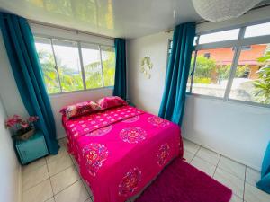 a bedroom with a pink bed in a room with windows at La Cabane de Hotu in Papeete