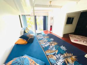 a room with a large blue bed with tropical pillows at La Cabane de Hotu in Papeete