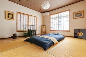 Un dormitorio con una cama grande en una habitación con ventanas. en 潮宿enjoykeys A private rental space with a Japanese garden, en Higashiōsaka