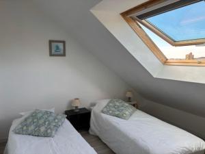 two beds in a room with a window at Appartement de charme à Étel, vue mer, 2 chambres - FR-1-479-220 in Étel