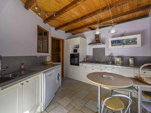 cocina con armarios blancos y techo de madera en Étel - Longère 7 pièces 150 m² - Wifi - Jardin clos - FR-1-479-225, en Étel