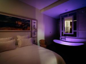 a bedroom with a white bed with a purple lighting at Appartement de charme, climatisé, animaux admis, centre historique de Pézenas - FR-1-607-215 in Pézenas
