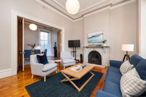 a living room with a blue couch and chairs and a fireplace at Saint Francis in Fitzroy in Melbourne