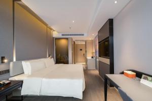 ein Schlafzimmer mit einem großen weißen Bett und einem Schreibtisch in der Unterkunft Atour Hotel Dalian North Station Huanan Plaza in Dalian