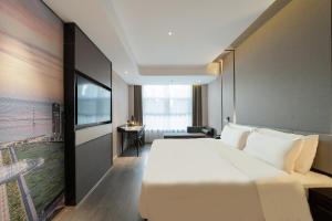ein Hotelzimmer mit einem großen Bett und einem Fernseher in der Unterkunft Atour Hotel Dalian North Station Huanan Plaza in Dalian
