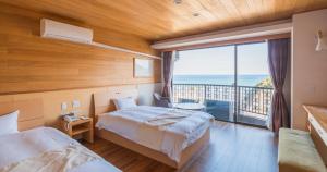 a bedroom with two beds and a large window at Hotel SEASONS NICHINAN in Nichinan