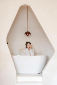 a woman is sitting in a white bath tub at EUPHORIA丨Quiet Garden Quiet Designer Garden Hotel丨Datang Never Sleeps City Big Wild Goose Pagoda Subway Station Branch丨Near the scenic area in Xi'an