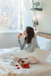 a woman sitting on a bed eating a piece of fruit at EUPHORIA丨Quiet Garden Quiet Designer Garden Hotel丨Datang Never Sleeps City Big Wild Goose Pagoda Subway Station Branch丨Near the scenic area in Xi'an