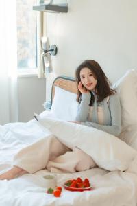 a woman sitting on a bed with a plate of fruit at EUPHORIA丨Quiet Garden Quiet Designer Garden Hotel丨Datang Never Sleeps City Big Wild Goose Pagoda Subway Station Branch丨Near the scenic area in Xi'an