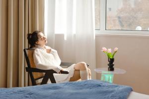 a woman sitting in a chair looking out of a window at EUPHORIA丨Quiet Garden Quiet Designer Garden Hotel丨Datang Never Sleeps City Big Wild Goose Pagoda Subway Station Branch丨Near the scenic area in Xi'an