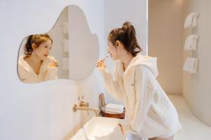 a woman brushing her teeth in front of a mirror at EUPHORIA丨Quiet Garden Quiet Designer Garden Hotel丨Datang Never Sleeps City Big Wild Goose Pagoda Subway Station Branch丨Near the scenic area in Xi'an