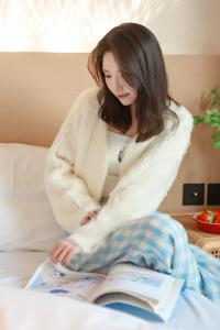 a woman sitting on a bed reading a book at EUPHORIA丨Quiet Garden Quiet Designer Garden Hotel丨Datang Never Sleeps City Big Wild Goose Pagoda Subway Station Branch丨Near the scenic area in Xi'an