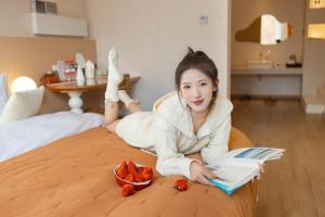 a woman laying on a bed with a book and fruit at EUPHORIA丨Quiet Garden Quiet Designer Garden Hotel丨Datang Never Sleeps City Big Wild Goose Pagoda Subway Station Branch丨Near the scenic area in Xi'an