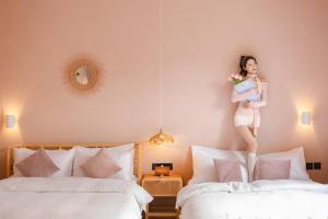 a woman is standing on top of two beds at EUPHORIA丨Quiet Garden Quiet Designer Garden Hotel丨Datang Never Sleeps City Big Wild Goose Pagoda Subway Station Branch丨Near the scenic area in Xi'an