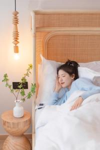 a young woman sleeping in a bed at EUPHORIA丨Quiet Garden Quiet Designer Garden Hotel丨Datang Never Sleeps City Big Wild Goose Pagoda Subway Station Branch丨Near the scenic area in Xi'an