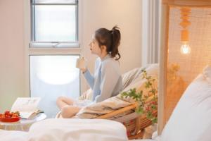 a young woman sitting on a bed eating an ice cream at EUPHORIA丨Quiet Garden Quiet Designer Garden Hotel丨Datang Never Sleeps City Big Wild Goose Pagoda Subway Station Branch丨Near the scenic area in Xi'an