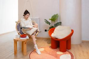 a woman sitting in a swing reading a book at EUPHORIA丨Quiet Garden Quiet Designer Garden Hotel丨Datang Never Sleeps City Big Wild Goose Pagoda Subway Station Branch丨Near the scenic area in Xi'an