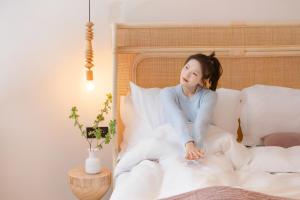 a woman sitting on a bed with pillows at EUPHORIA丨Quiet Garden Quiet Designer Garden Hotel丨Datang Never Sleeps City Big Wild Goose Pagoda Subway Station Branch丨Near the scenic area in Xi'an