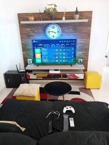 a living room with a tv and a table with a controller at Apartamento centralizado à poucas quadras do mar. in Tramandaí