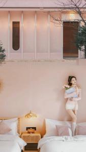 a woman is standing on a wall between two beds at EUPHORIA丨Quiet Garden Quiet Designer Garden Hotel丨Datang Never Sleeps City Big Wild Goose Pagoda Subway Station Branch丨Near the scenic area in Xi'an