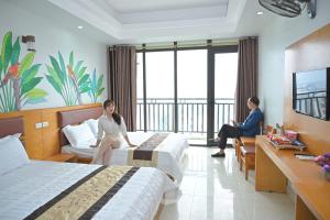a hotel room with two women sitting on beds at UFJ HOTEL Sầm Sơn in Sầm Sơn