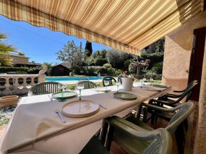 tavolo con tovaglia e sedie bianche e piscina di Charming Provençal Villa with pool and garden a Mougins