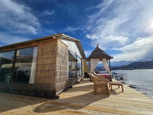 a wooden deck with a gazebo and chairs on the water at Samca Titicaca Lodge Puno Peru in Puno