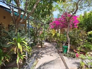 a path through a garden with pink flowers at Nhà Nghỉ Sứ Trắng in Ấp Thiện Phước
