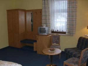 a room with a tv and a couch and a chair at Hotel Stadt Suhl in Zella-Mehlis