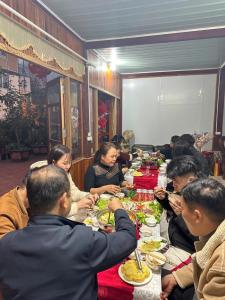 a group of people sitting at a long table eating food at Cầu Treo Homestay in Cham Ta Lao +35 photos