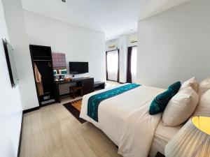 ein weißes Schlafzimmer mit einem Bett und einem Schreibtisch in der Unterkunft Hotel Roditha Banjarbaru in Banjarbaru