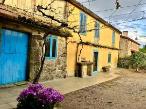 una casa con una puerta azul y flores púrpuras en Casa do Bidueiro, en Luou