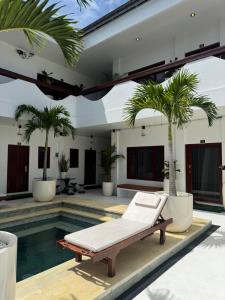 - une piscine avec chaise longue à côté d'une maison bordée de palmiers dans l'établissement Uluwatu Stay's Standard Room #3, à Uluwatu