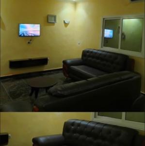 a living room with a black couch and a tv at Résidence MK in Motsouémbé