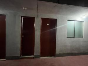 three brown doors in a room with a wall at Habitación 2 camas in Ayacucho
