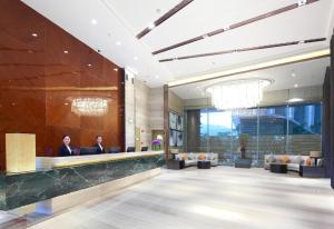 a lobby of a hotel with two people sitting at desks at Huafa Place in Zhuhai