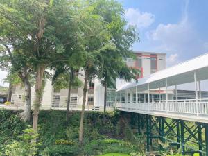 a bridge in front of a building with trees at โรงแรมธาราคีรีเพลส in Ban Pang Kae