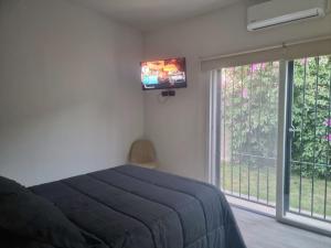 a bedroom with a bed and a television on the wall at La casa de Flor in San Martín
