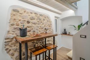 a stone wall in a kitchen with a table and stools at VicoloSuite - Lago di Garda in Torri del Benaco