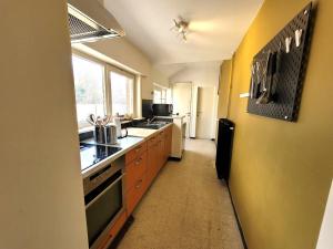a kitchen with orange cabinets and a yellow wall at Vakantiewoning dEreplatse in Zuienkerke
