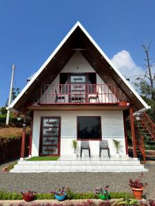バガモンにあるVerdant peaks Homestayの椅子2脚とバルコニー付きの家