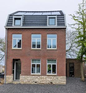 een rood bakstenen huis met een zwart dak bij Mijn appartement met sauna en lift in Voerendaal