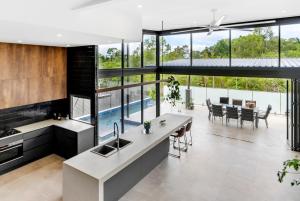 a kitchen and dining room with a view of a pool at Belle Escapes Bluewater Breeze in Trinity Beach