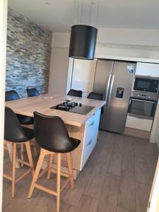 a kitchen with a island with chairs and a stove at Chambre privé chez lhabitant in Montauban