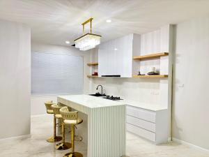 a kitchen with white cabinets and a counter with stools at Dream pool villa 5 in Jomtien Beach