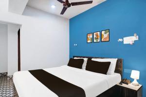 a bedroom with a large bed with a blue wall at Super Hotel O Noonmati Guwahati Formerly Hotel Sundari in Guwahati